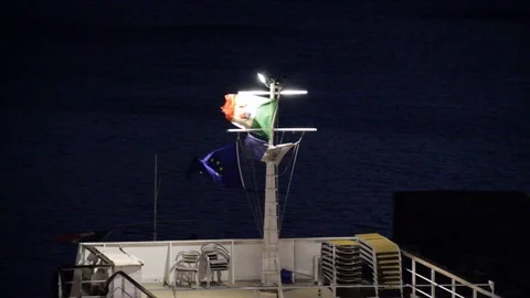 Flags in the wind at night in front of the sea Stock Footage 105588698
