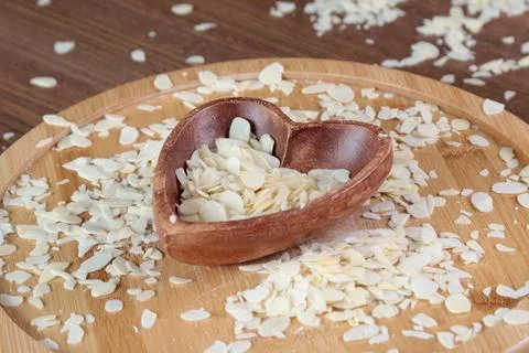 Flake sliced almonds in heart shaped wooden stand. Wooden dishes and healthy Stock Photos