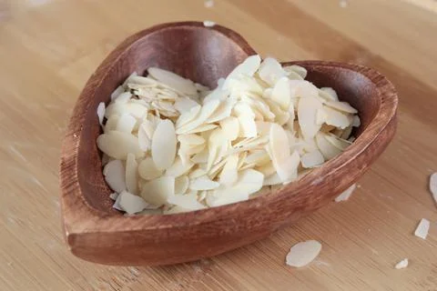 Flake sliced almonds in heart shaped wooden stand. Wooden dishes and healthy Stock Photos