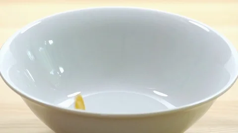 Flakes falling into a white bowl Stockbeeldmateriaal 79001816