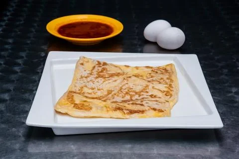 Flaky Egg Prata or egg paratha with Curry Sauce and Fresh Eggs on a White P.. Stock Photos