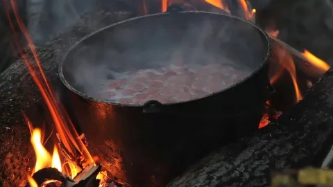 Flame around the pot. in the evening to cook on the fire. in a pot standing on Stock Footage