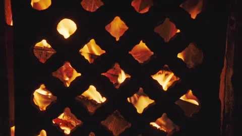 Flame blazing inside stove or fireplace behind metal grate Stock Footage 344696325