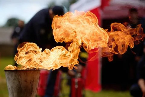 Flame Burst. A dramatic burst of fire from a torch against an outdoor backdrop. Stock Photos