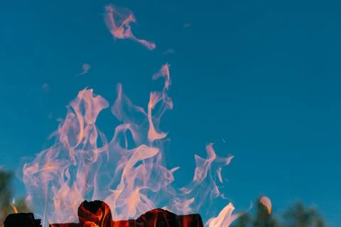 Flame of campfire outside with blue sky in background. Bonfire Foto stock