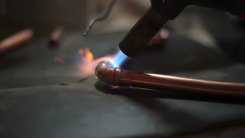 Flame from a gas blowtorch being applied to a copper pipe fitting, to melt 스톡 동영상 148998652