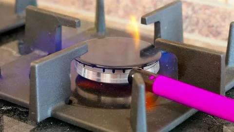 The flame of a gas burner on a stove in the kitchen is ignited by a lighter Stock Footage 229426073