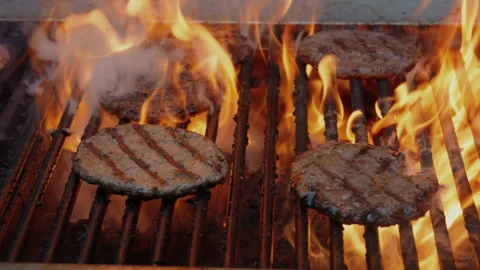 Flame grilled burger being flipped with flare up on hot charcoal BBQ commercial Stock Footage 328718278