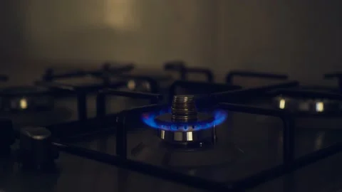 Flame of kitchen burner with gas fire on stove with stack of coins Stock Footage 202528544