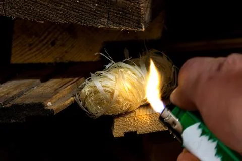 Flame from lighter ignites fire starter to initiate combustion of surrounding Stock Photos
