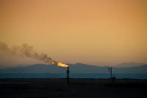 Flame from an oil pipe at sunset. Stock Photos