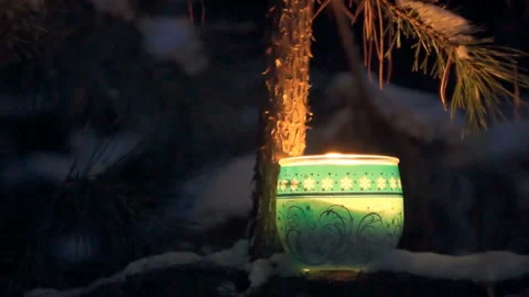 The flame of a paraffin candle in the wind in a dark winter snowy forest Stock Footage 86063497