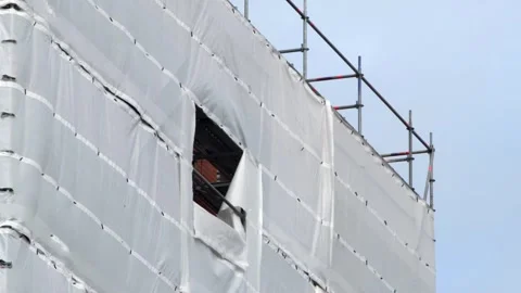 Flame retardant scaffold sheeting wrapped building in england uk Stock Footage 268822089