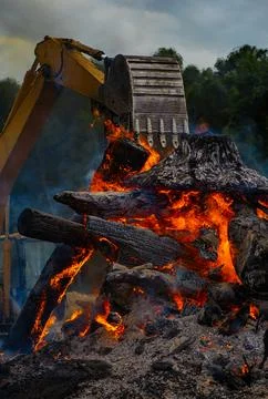 Flame rises through burning debris. Flame burns beside intense flames. Exca.. Stock Photos