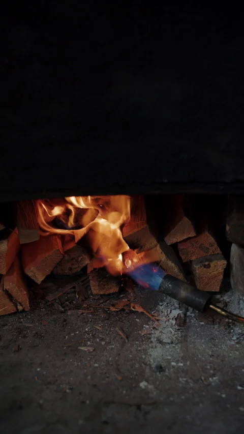 Flame from torch igniting stacked firewood under smoker Stock Footage 306960868