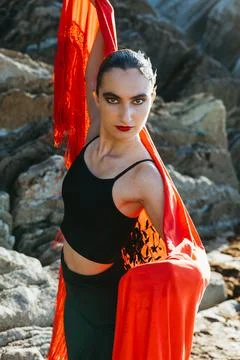 Flamenco dancer with red shawl posing at sunset on rocky coast Stock Photos