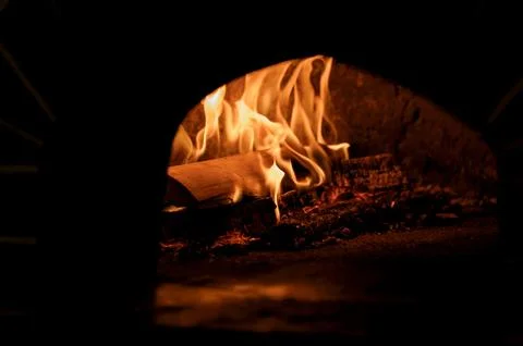 Flames burning inside a rustic stone fireplace with logs and embers Foto stock