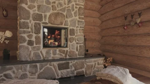 Flames burning in a modern stone fireplace inside a rustic wooden chalet living Vidéo 335199107