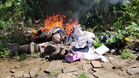 Flames consume discarded items in an open area Stock Footage 330717852