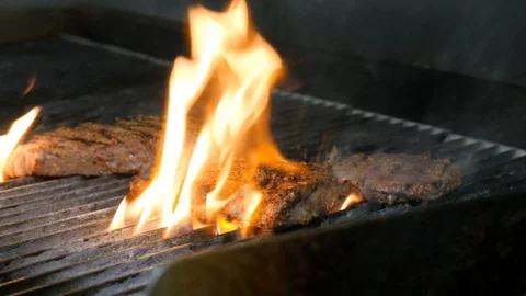 Flames cooking steaks on professional grill Stock Footage 94264751