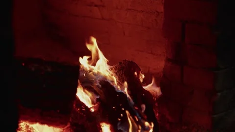 Flames dance around burning logs in a brick fireplace, showcasing the vibrant Vídeo Stock 332724218