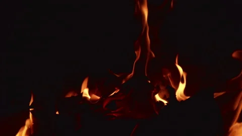Flames dance brightly in a dark space as logs burn slowly and steadily Video stock 344318487