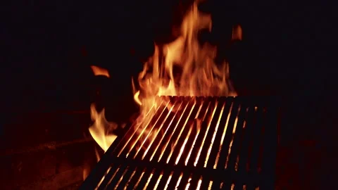 Flames dance on a grill during a night cookout in the backyard with friends Stock Footage 342369441
