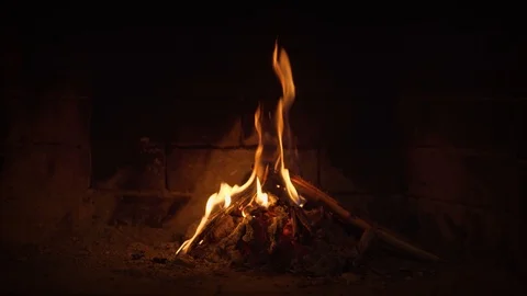 Flames dance over split logs, illuminating hearth and brick backwall Video stock 100301199