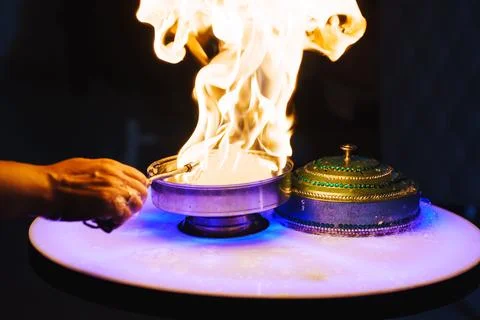 Flames dance on a table during a cooking demonstration Stock Photos