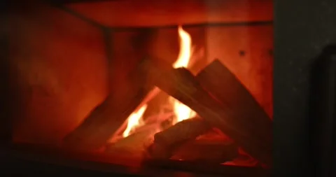 Flames dancing around logs catching fire inside metal stove firebox, releasing Stock Footage 345070388
