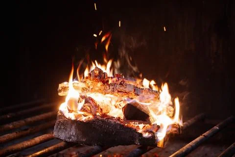 Flames dancing on burning logs in a grill, creating a warm Stock Photos