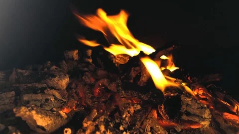 Flames dancing in a dark firepit with a blazing pile of hot coals Stock Footage 118349525