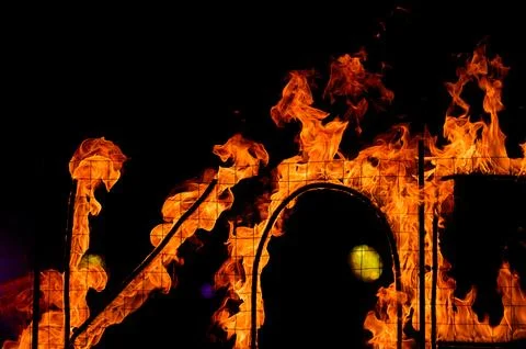 Flames engulfing structure at night, bright orange fire against dark backgrou Stock Photos