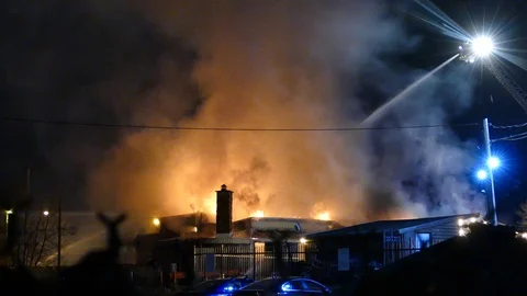 Flames from an evening fire at lighting up the smoke on night sky Video stock 129987118