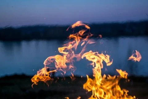 The flames of the fire burning the herb in the evening field, turning into co Stock Photos