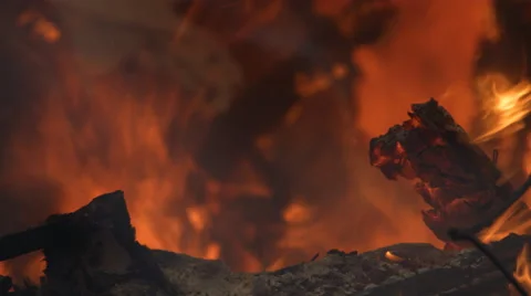Flames flare above the ash-coated charred rubble of a house fire Stock Footage 59222008