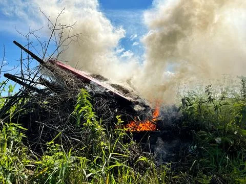 Flames flicker and smoke rises from a burning debris pile Foto stock