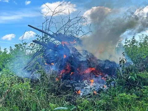 Flames flicker and smoke rises from a burning debris pile Foto stock