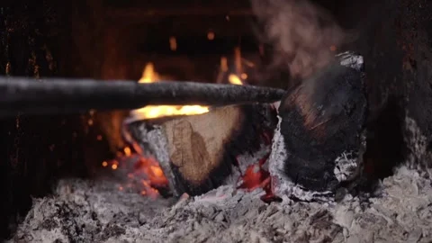 Flames flicker as a log is repositioned in a fireplace, revealing glowing embers Stock Footage 327855717