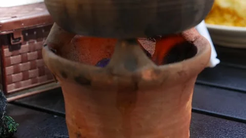 Flames flicker under a clay pot on a simple wooden stove, symbolizing tradition Stock Footage 312108894