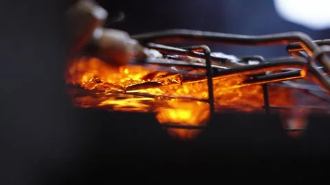Flames glowing beneath a grill as meat cooks, producing smoke and flavor, slow Stockbeeldmateriaal 304591398