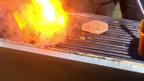 Flames leap from a sizzling burger patty Stock Footage 333937025