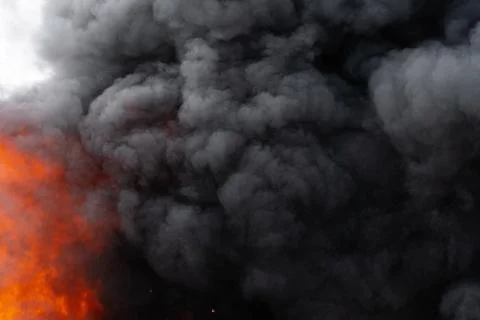 Flames of red fire and motion blur clouds of black smoke covered sky Stock Photos