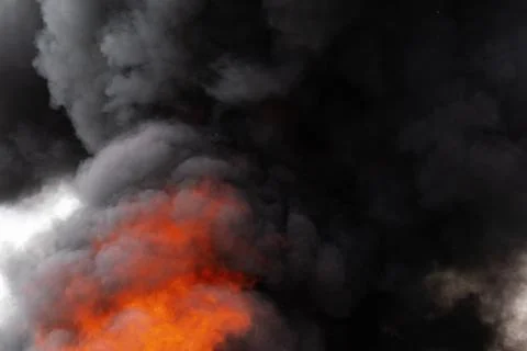 Flames of red fire and motion blur clouds of black smoke covered sky Foto stock