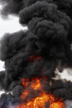 Flames of red fire and motion clouds of black smoke covered sky Stock Photos