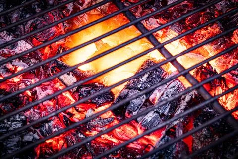 Flames rising through a barbecue grate above hot charcoal Stock Photos