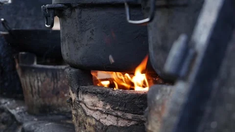 Flames roar under a soot-covered pot used in daily meal preparation at an Stock Footage 313485901