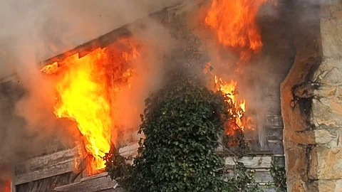 Flames shooting out of second story window at house fire Stock Footage 73433175