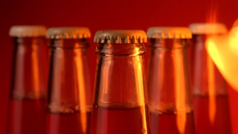 Flames sparkle in front of five glass bottles in dark against a red background Stock Footage 150712510