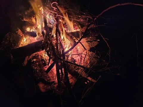 Flames of a stone pit fire at night in dark background at a campground Stock Photos